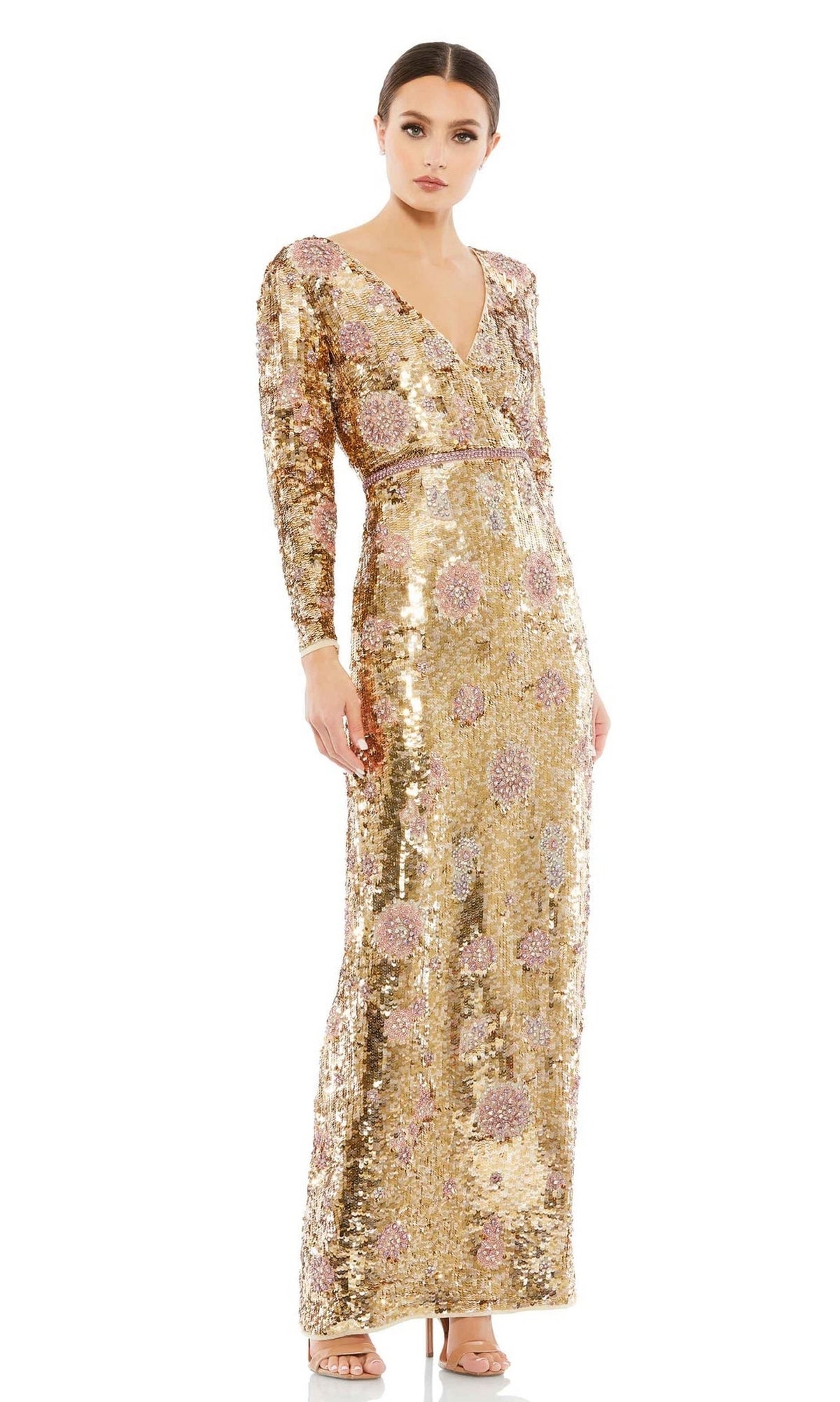 A woman wears the Long Formal Dress 93615 by Mac Duggal—a gold sequin, long-sleeve, floor-length gown with pink floral patterns and a V-neckline—standing against a white background.